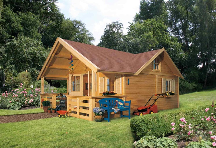 Drevený záhradný domček s terasou, záhradným nábytkom a záhradným náradím na trávniku.