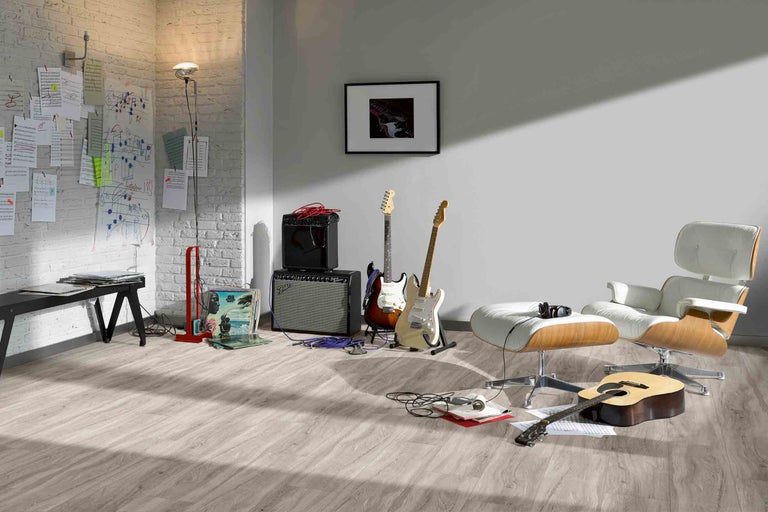 Obývacia izba s vinylovou podlahou s dreveným vzhľadom, gitarami, zosilňovačmi a kreslom s podnožkou