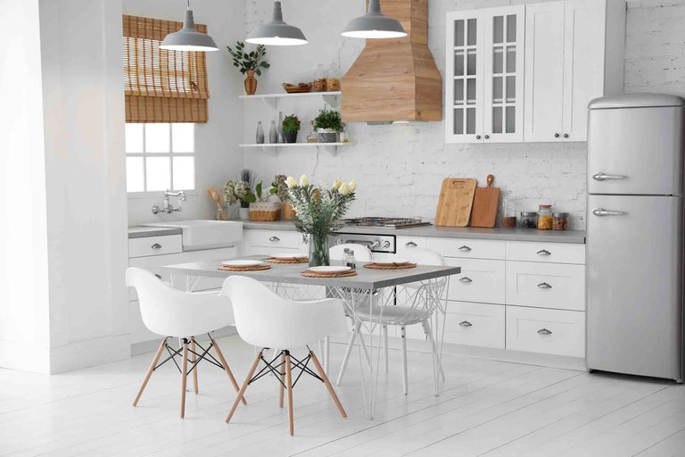 Svetlá kuchyňa s jedálenským stolom, stoličkami, kuchynskou linkou a dekoráciou