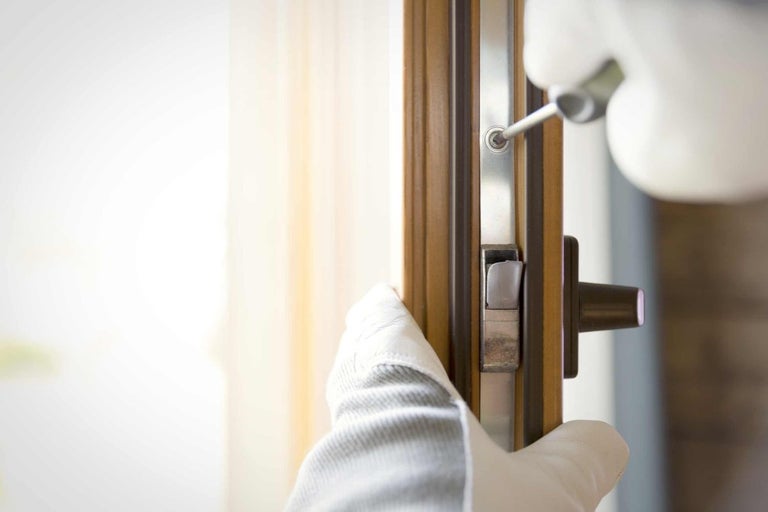 Pracovník montuje zámok dverí pomocou skrutkovača