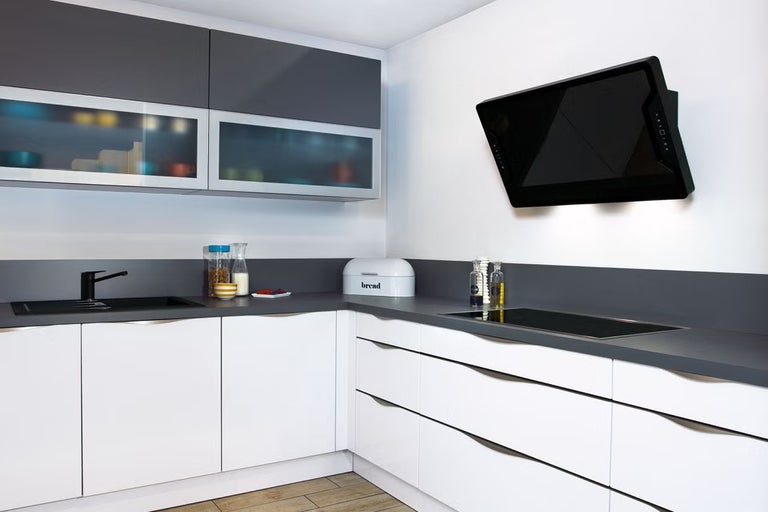 Moderná kuchyňa s bielymi spodnými skrinkami, sivými pracovnými doskami a čiernym digestorom