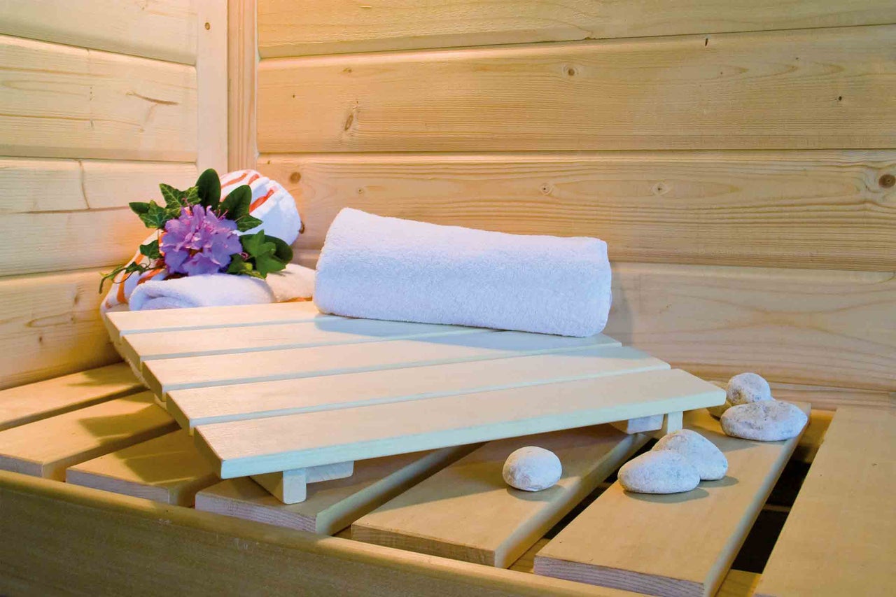 Sauna s drevenými stenami, uterákmi, kameňmi a lavicou