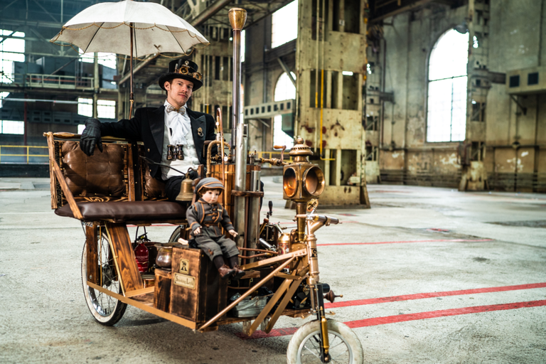 Muž v steampunkovom oblečení na zákazkovej trojkolke s bábikou a dáždnikom v sklade