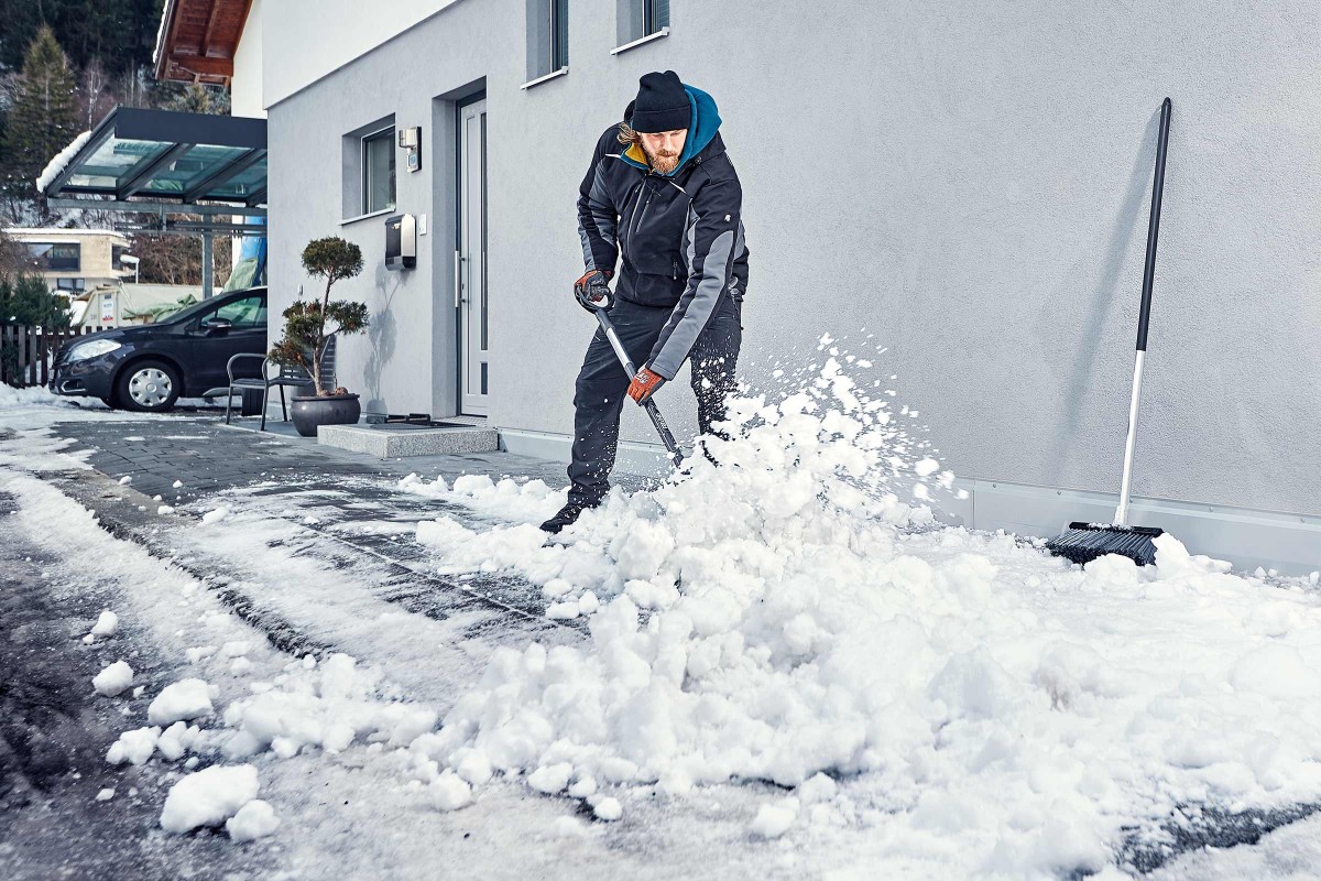 Muž odhadzuje sneh pred domom pomocou snehovej lopaty