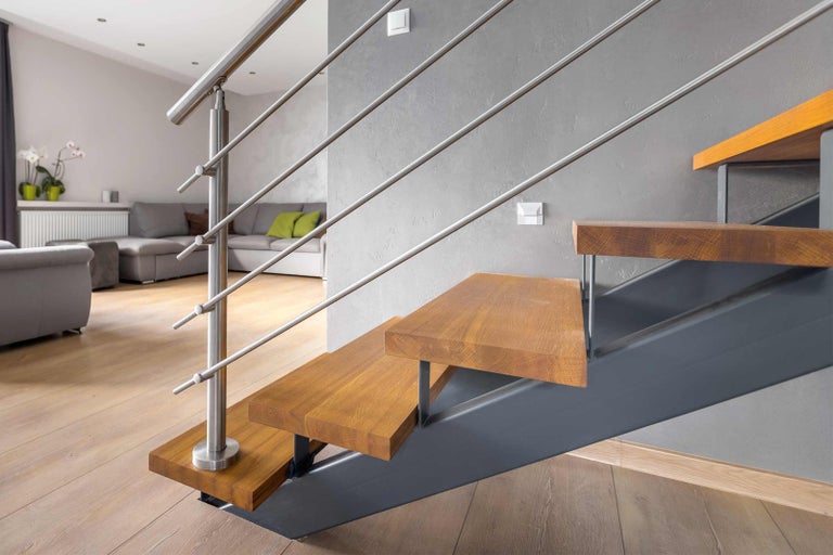 Schodisko s drevenými stupňami a nerezovým zábradlím v modernom obývacom priestore
