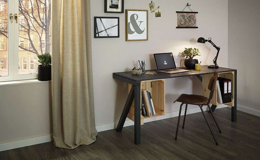 Pracovňa so stolom z drevených debničiek, stolnou lampou a kancelárskou stoličkou