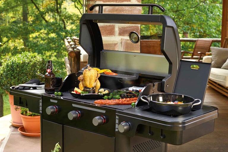 Čierny plynový gril s jedlom pripraveným vonku.