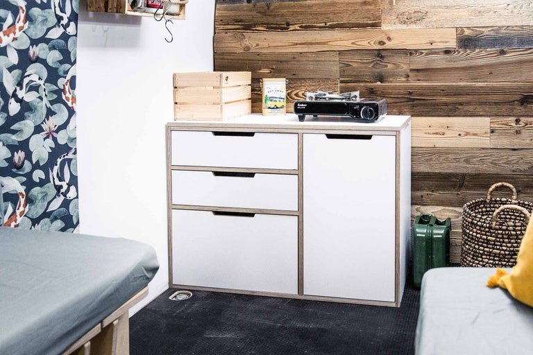 Skrinka s tromi zásuvkami a jednými dverami, drevená debna, benzínový varič a dekorácia na pracovnej doske