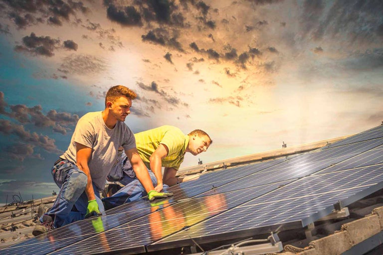 Dvaja montéri inštalujú solárne panely na strechu.