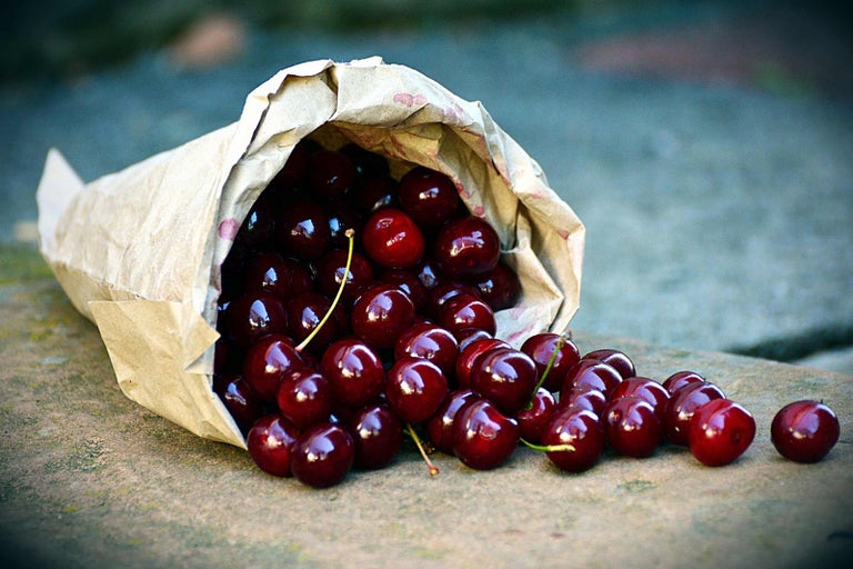 Papierové vrecko s čerešňami leží na povrchu.