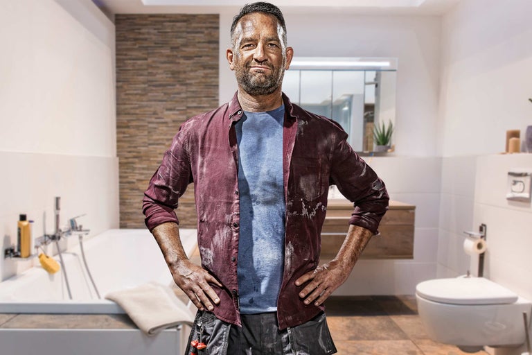 Remeselník v kúpeľni s vaňou, toaletou a skrinkou pod umývadlo