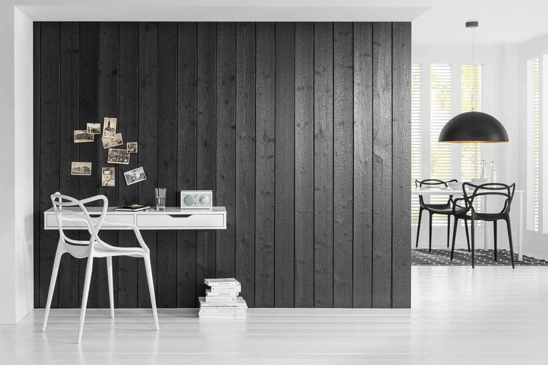 Svetlá izba s čiernou drevenou stenou, písacím stolom, stoličkou a jedálenským kútom.