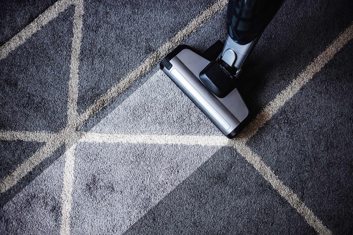 Vysávač na sivom koberci s geometrickým vzorom