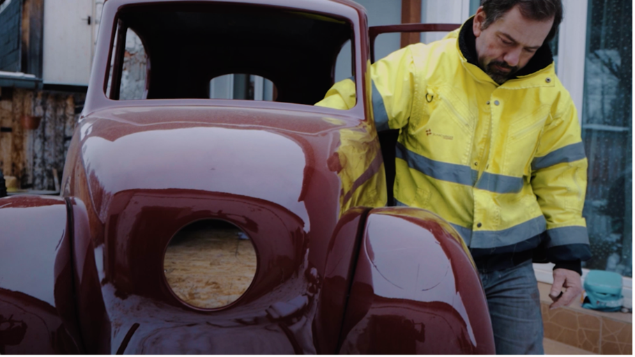 Muž reštauruje červené veterán auto.