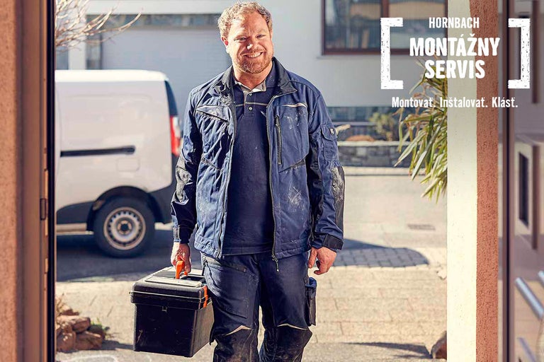 Remeselník s kufríkom na náradie pred domom pre montážny servis Hornbach.