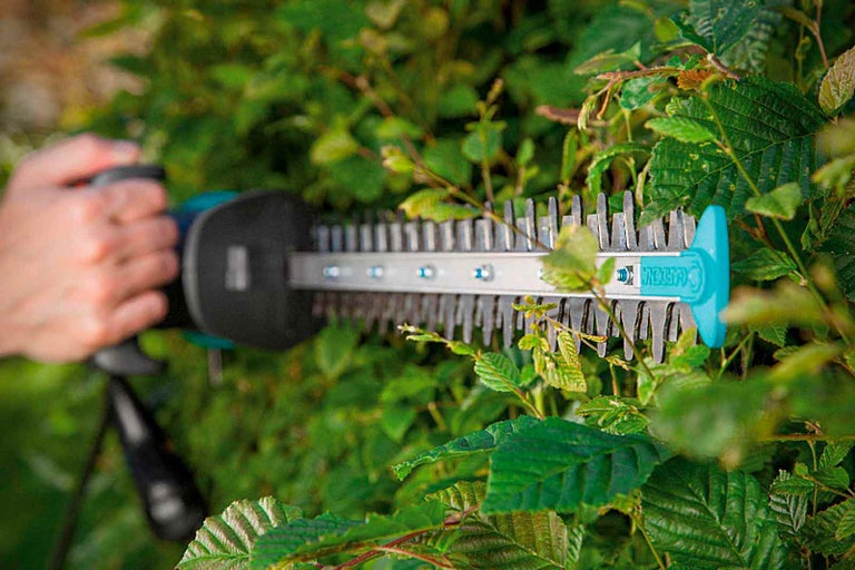 Obsluha nožníc na živý plot pri strihaní živého plota.