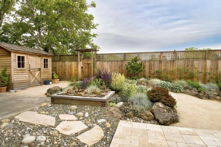 Upravená záhrada so záhradným domčekom, dreveným plotom a rôznymi rastlinami