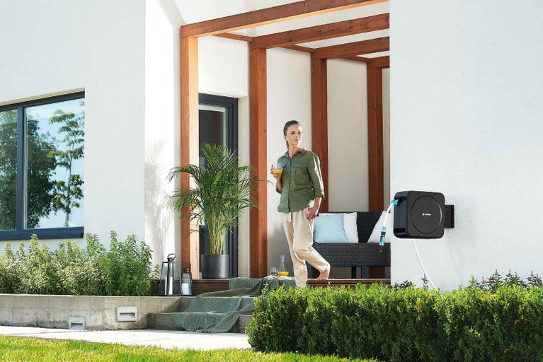 Terasa s automatickým navijakom hadice, ženou a kvetináčom