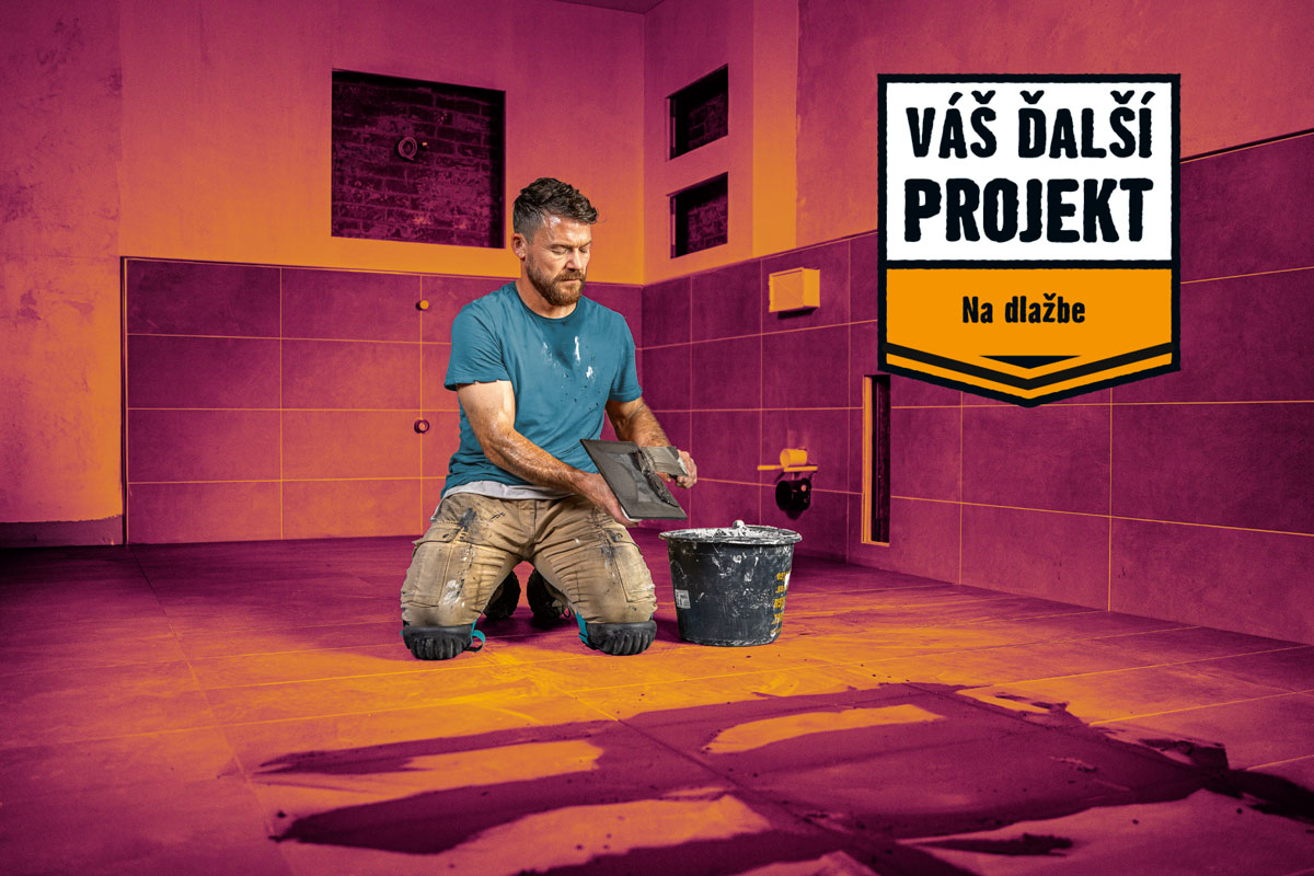 Muž pokladá dlaždice v kúpeľni. Na podlahe sú už položené dlaždice. K dispozícii je vedro a náradie.