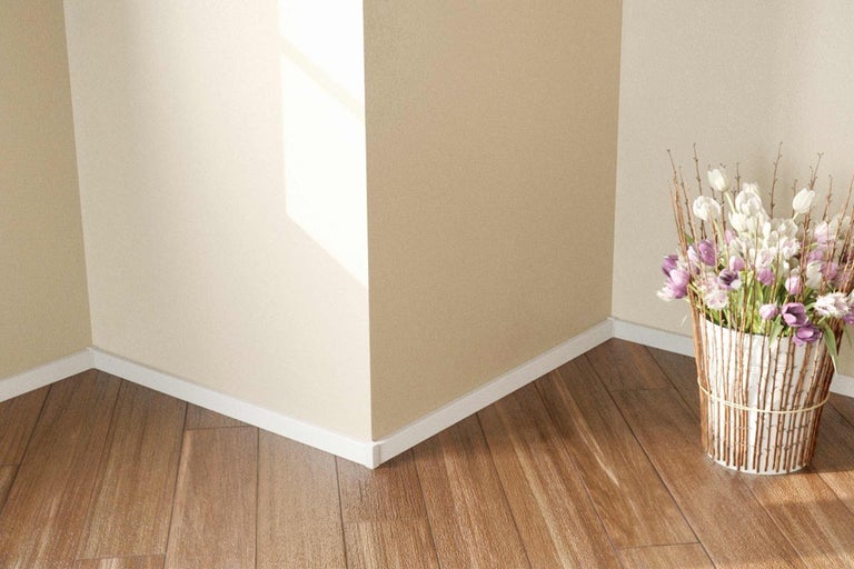 Roh miestnosti s bielymi podlahovými lištami a drevenou podlahou