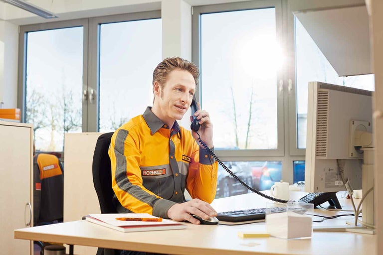 Zamestnanec spoločnosti Hornbach telefonuje pri stole.