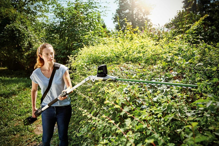 Žena strihá živý plot akumulátorovými nožnicami na živý plot v záhrade