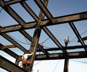 Stavenisko s oceľovými nosníkmi a stavebnými robotníkmi