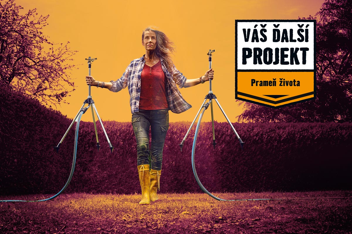 Žena drží dva statívové zavlažovače v záhrade, v pozadí je živý plot