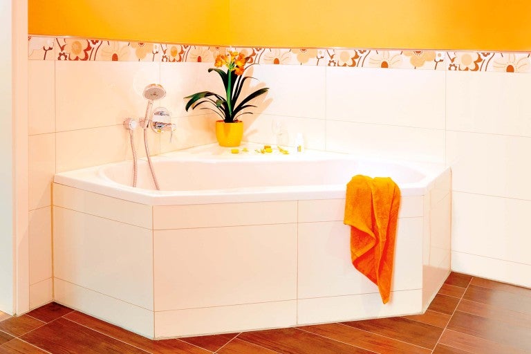 Rohová vaňa s uterákom a armatúrou v kúpeľni s obkladmi