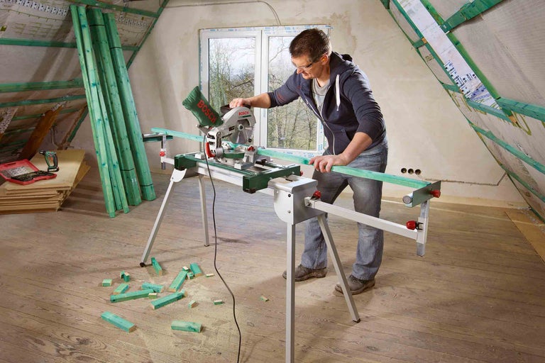 Osoba pracuje s pokosovou pílou v podkroví na rezanie dreva.