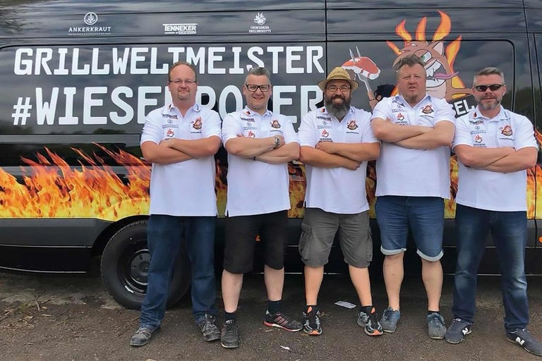 Päť ľudí stojí pred grilovacím vozidlom s nápisom Grillweltmeister.