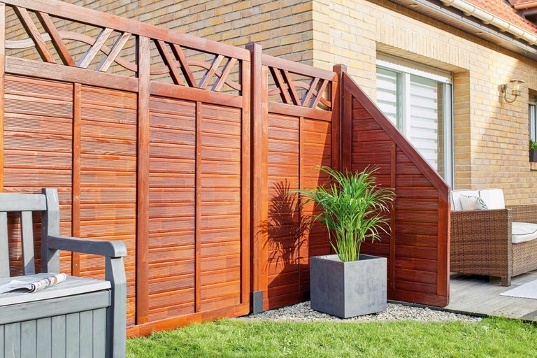 Drevený plot v záhrade s lavičkou a rastlinou v kvetináči