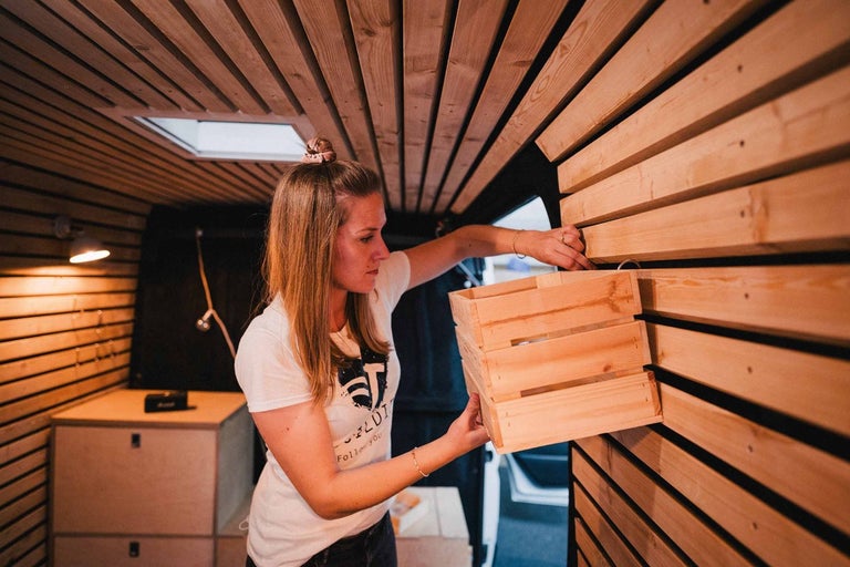 Žena pripevňuje drevenú debničku na drevené obloženie vnútri dodávky