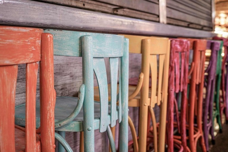 Niekoľko farebných drevených stoličiek stojí v rade.