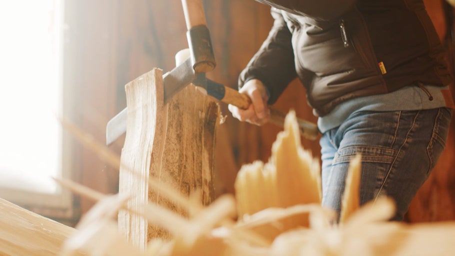 Osoba štiepa drevo pomocou klinu a kladiva