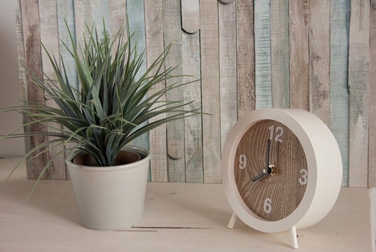 Dekoratívna scéna s umelou rastlinou v kvetináči a stolovými hodinami