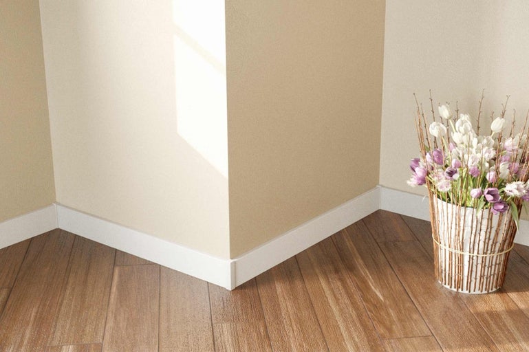 Roh miestnosti s drevenou podlahou, bielymi podlahovými lištami a kvetinovou aranžmán
