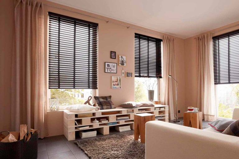 Obývacia izba s drevenými žalúziami, závesmi a nábytkom z paliet