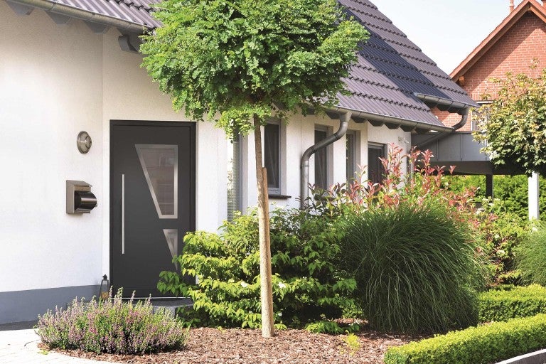 Fasáda domu s vchodovými dverami, poštovou schránkou a záhradou