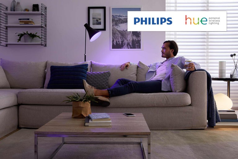 Muž relaxuje na gauči s osvetlením Philips Hue v obývacej izbe