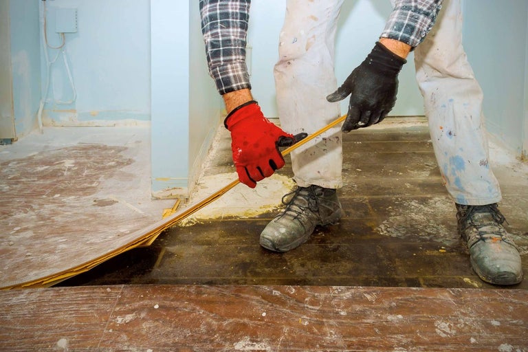 Remeselník pokladá drevenú dosku na podlahu