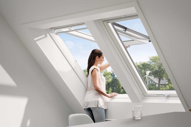 Žena otvára strešné okno pre denné svetlo a vetranie