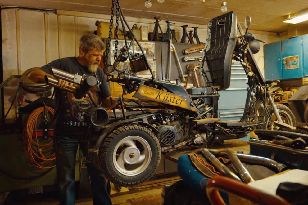 
				Willi vo svojej dielni niečo skrutkuje na motokáre, ktorú postavil.

			