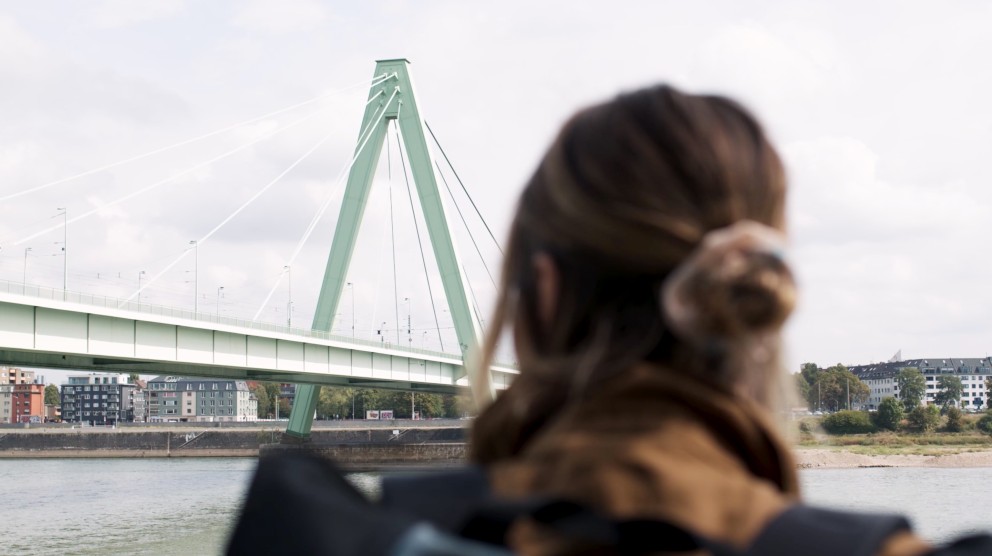 
				Anna stojí pri Rýna a pozerá sa na oceľový most.

			