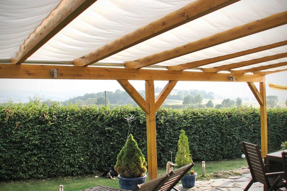 Drevená pergola so slnečnou plachtou v záhrade