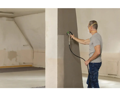 Muž maľuje stenu pomocou striekacej pištole