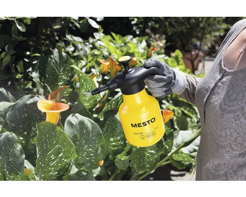 Osoba používa žltý tlakový postrekovač Mesto na starostlivosť o rastliny.