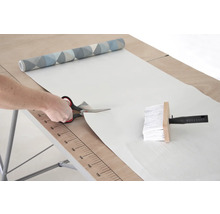 Rezanie tapety nožnicami na tapetovacom stole