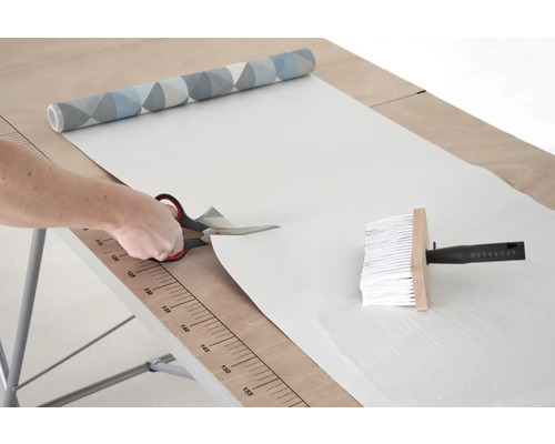 Rezanie tapety nožnicami na tapetovacom stole