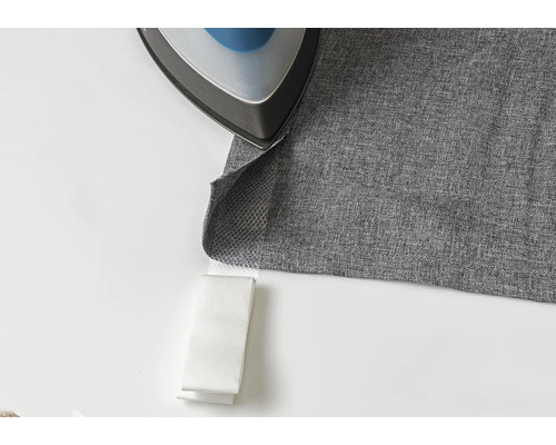 Žehlička na sivej látke s nažehľovacou páskou